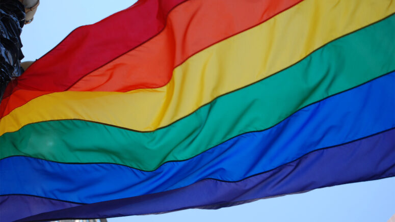 A close up on a waving rainbow pride flag.