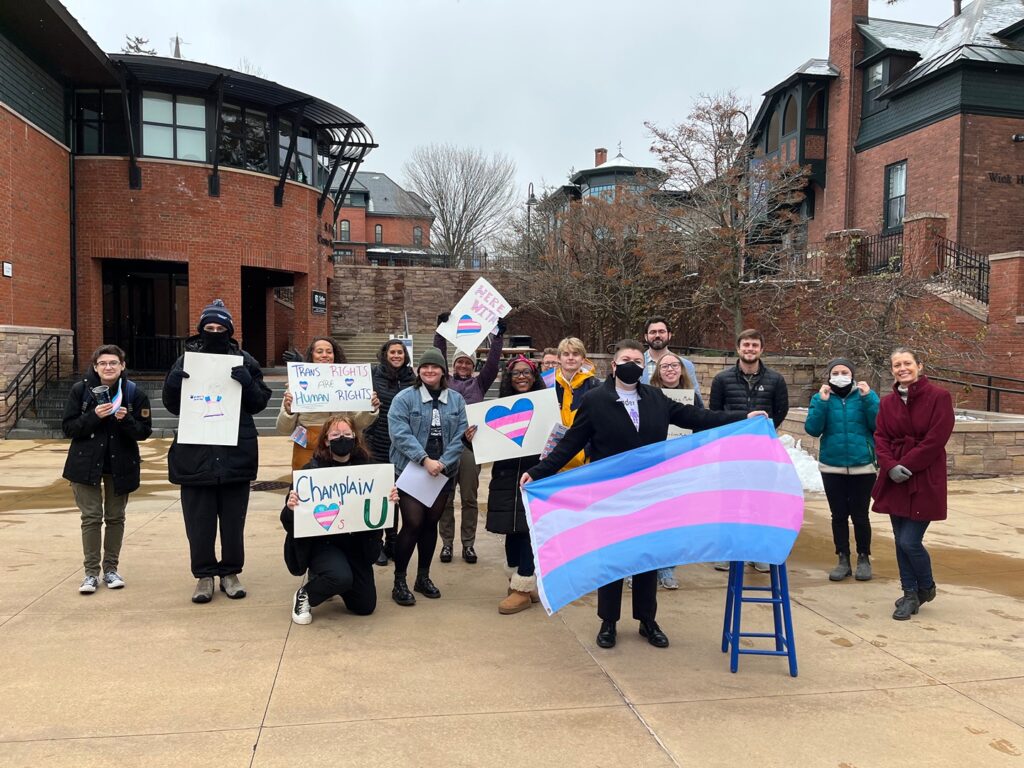 Participants of a Fall 2022 March for Trans Lives through Campus pose with signs and flags.